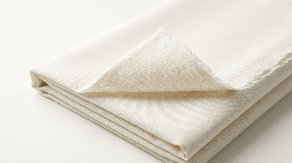 The Ivory Dusk — folded fabric yardage showing luminous off-white weave